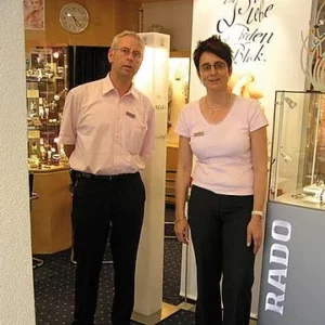 Zwei Mitarbeiter im Juweliergeschäft vor Vitrinen mit Schmuckstücken